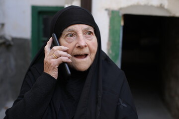 Surprised looking senior muslim woman making a phone call