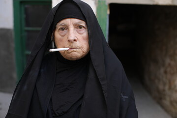 Senior muslim woman smoking a cigarette 