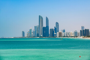 Panoramic view of Abu Dhabi with sea, waterfront Corniche, skyscrapers during summer sunny day in United Arab Emirates