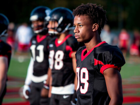 Side angle of American high school football players ready in equipment.