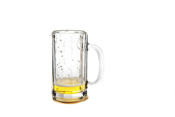 A empty glass beer stein with a bit of beer left and remaining flecks of foam isolated on white