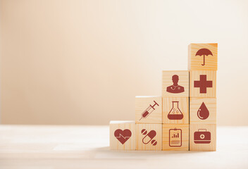 Wooden cubes stacked in a pyramid shape, embodying the healthcare and insurance concept. Atop, a medical insurance icon signifies protection. Blue background offers copyspace for Health Insurance idea - obrazy, fototapety, plakaty