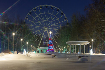 Low-angle view of an unlit wheel with a Christmas tree Ferris wheel at night
