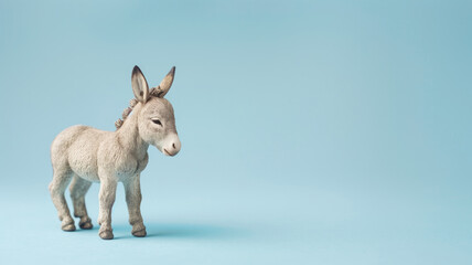 Small toy donkey stands against plain light blue background, looking to side