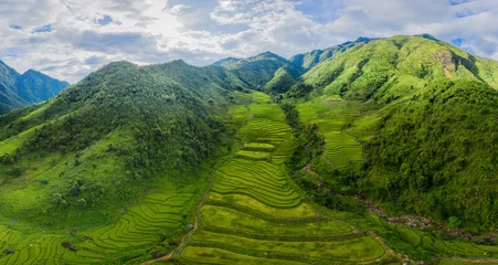 Poster Aerial top view of Fansipan mountains with paddy rice terraces, green agricultural fields in countryside or rural area, hills valley at sunset in Asia, Sapa, Vietnam. Nature landscape background. © FaiV007
