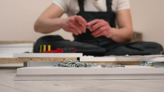 Furniture assembly. Furniture assembler reads instructions, assembly manual, begins assembly tightens Euros crews. Collector furniture. Moving concept, furniture assembly service, home improvement. 