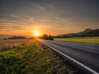 Empty asphalt road in a rural landscape at sunset