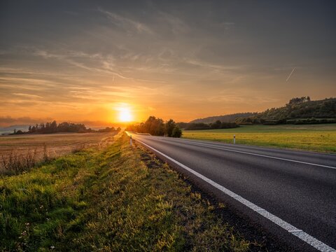 Empty asphalt road in a rural landscape at sunset - Powered by Adobe