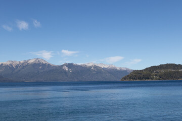 Calm and relaxing horizontal view of mountain range full of dense forests reflecting onto a lake's crystaline tranquil water wallpaper