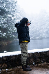 Fototapeta na wymiar Latinx traveler braves adverse weather, documenting snowy scenery in Sierra de Guadarrama.