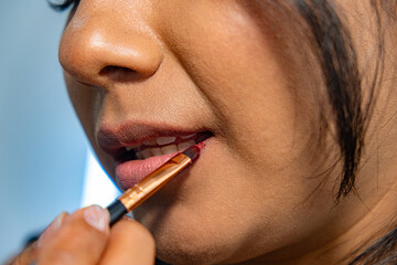 close-up of a woman painting her lips with a brush - beauty concept