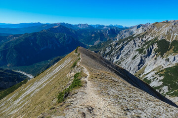 Idyllic hiking trail along golden alpine meadow with panoramic view of majestic Hochschwab massif,...