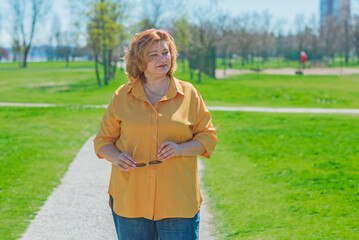 Plus size middle age lady in yellow shirt and blue jeans. Fashionable woman in casual style