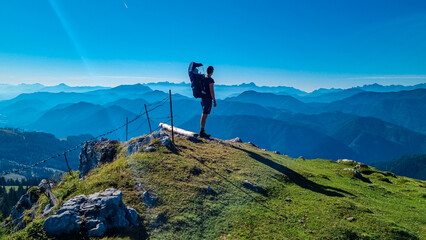 Man with baby carrier looking at magical mountain peaks of Karawanks and Julian Alps seen from...