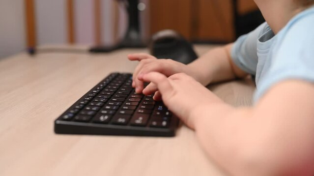 Children's fingers are typing something on the keyboard while adults are not around. Computer unattended in the hands of a child