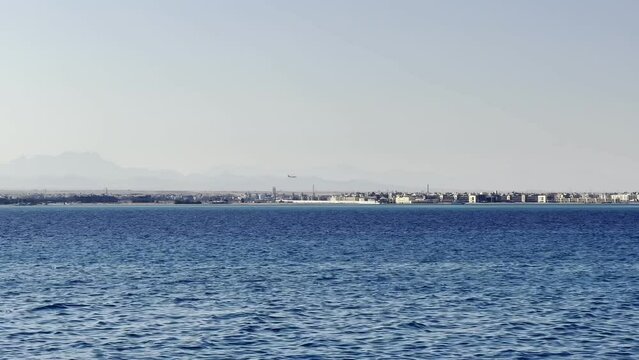Distant View Of An Airplane Landing At Hurghada Airport View From The Red Sea In Egypt. Wide Shot