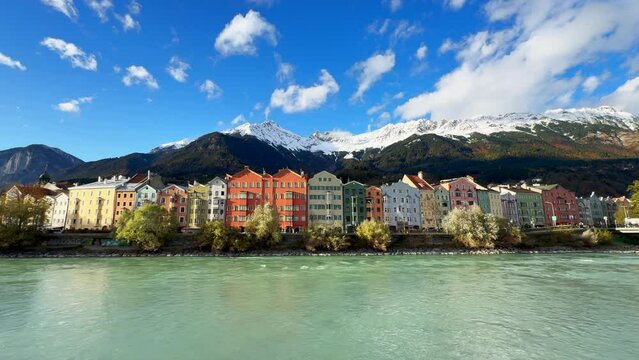 Innsbruck Austria colorful pastel buildings capital Tyrol Tyrolean Alps mountain backdrop the bridge over the Inn River cars bikes people sunny blue sky clouds October November autumn fall wide static