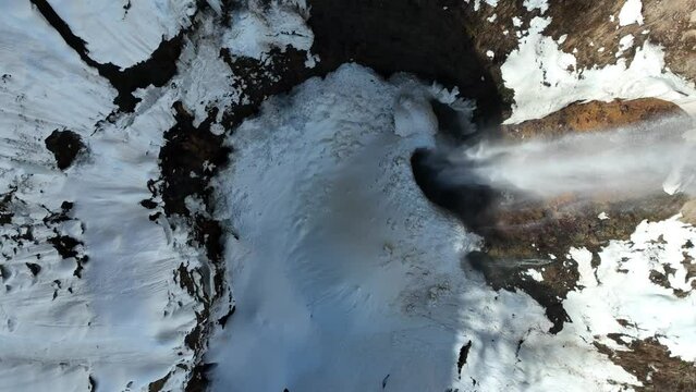 Top down shot of waterfall from melting snow, drone ascending revealing size of waterfall. Japan mount myōkō a volcanic mountain in Myoko-Togakushi Renzan National Park region