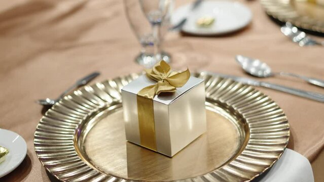 A small gift box for guests next to cutlery at a wedding dinner