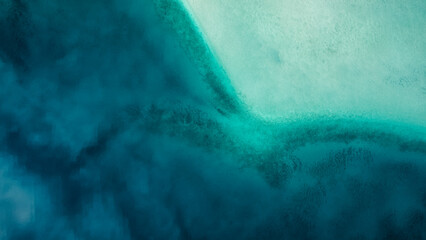 Abstract view of deep blue water and shallow teal water from drone
