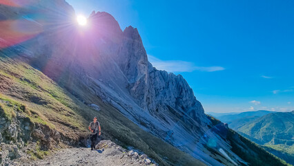 Hiker man with panoramic view of majestic mountain cliff Schartenspitze in untamed Hochschwab...