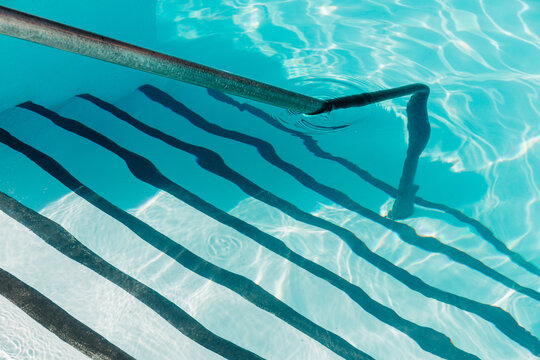 Pool stair steps and hand rail on summer day