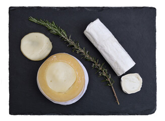 Top view of a blackboard with two different types of broken cheese, small sprig of rosemary between the cheeses