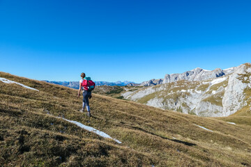 Hiker woman on scenic hiking trail along idyllic alpine meadow to Foelzkogel in wild Hochschwab...