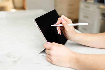 Hand with stylus drawing on a tablet