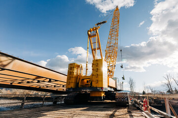 Yellow construction crane atop bridge construction site