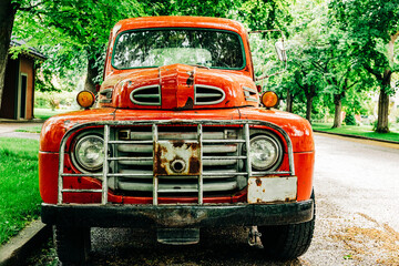 Vintage orange truck parked on tree lined street
