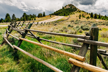 Curved dirt road and wood fence leading to Big Butte