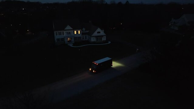 Delivery truck in front of mansion in USA at night. Aerial orbit of unrecognizable courier service.