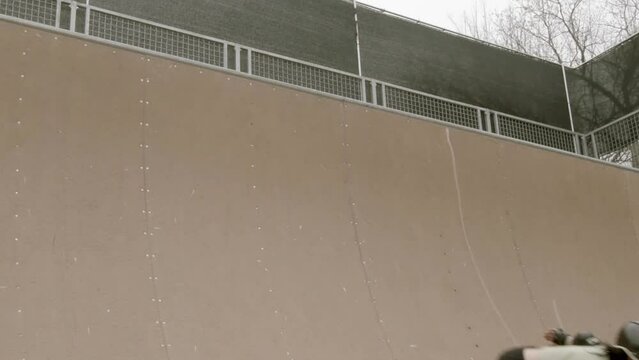 Fixed shot of female roller skater moving in and out of frame doing expert tricks on Corey Lawrence halfpipe vert ramp in Lawrence, Kansas, USA.
