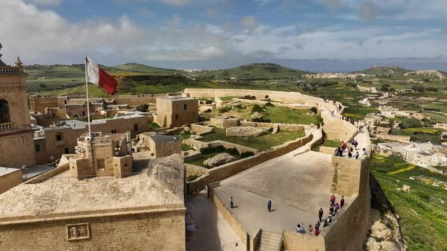 Zoom-out drone shot of the Citadel in Victoria, Gozo, with people on it.