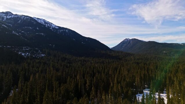 Scenic view above evergreen forest and snow with mountain range in the background in Cle Elum during dusk in Washington State
