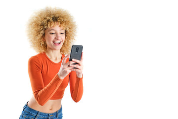 young girl with blonde afro hair smiling using her smart phone on white background - obrazy, fototapety, plakaty