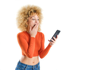 young girl with blonde afro hair with surprised face looking at her smart phone on white background - obrazy, fototapety, plakaty