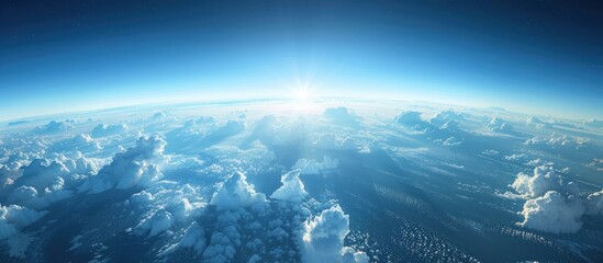 A view from a plane showing the sun shining brightly above a blanket of clouds in the sky.