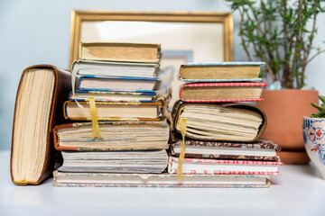 A variety of used journals stacked on a white desk