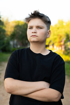 Portrait serious teenager with fresh haircut, black tee, crossed arms