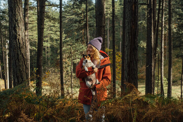 Woman Hiker Carrying Her Dog in Forest 