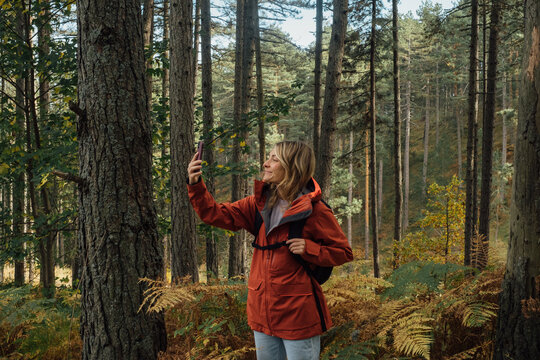 Young Woman Hiker Taking Picture With Mobile Phone in Forest