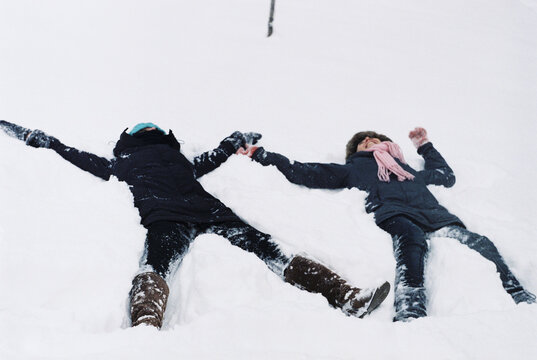 Sisters make snow angels in the snow