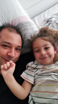 Ugc selfie of dad and daughter lying in bad