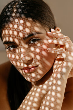 Stylish woman in spotted shadow light looking at camera