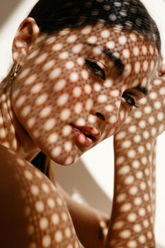 Romantic woman in red lips touching head under spotted light shadow