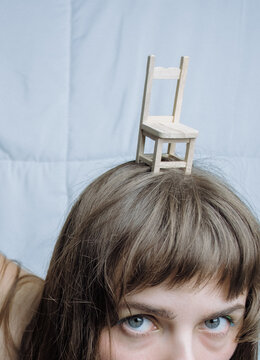 Miniature chair on woman's head. Alice in wonderland homage. 