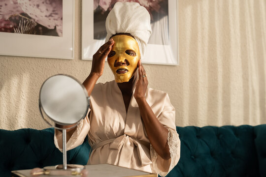 Black woman applying hydrogel face skin care mask 