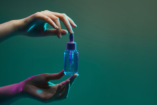 hand holding bottle with pipette and drop of oil
